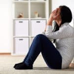 unhappy woman sitting on floor and crying at home