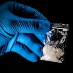 illicit fentanyl in small bag held by hand in blue glove