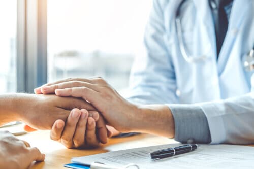 Doctor holding hand of patient to offer comfort