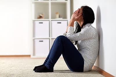 unhappy woman sitting on floor and crying at home